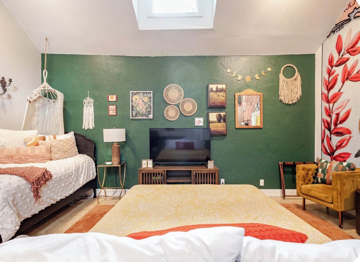 Een slaapkamer met een bed, een televisie, decoratie aan de muur en een stoel.