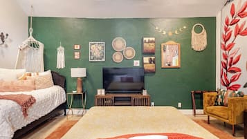 Een slaapkamer met een bed, een televisie, decoratie aan de muur en een stoel.