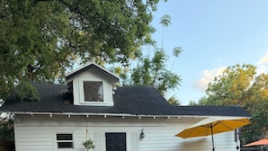 A small white house with a black door, a window, and a porch with a yellow umbrella. - “The Clementine” Boho Home in Orlando’s Food Scene (Orlando)
