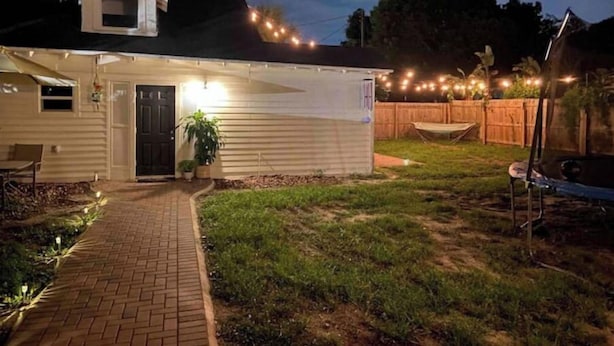 A single-story house with a covered porch, a brick pathway leading to the entrance, and a fenced backyard. - “The Clementine” Boho Home in Orlando’s Food Scene (Orlando)