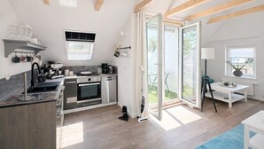 A modern kitchen with built-in appliances, a dining area with a table and chairs, and a sliding glass door leading to a patio.