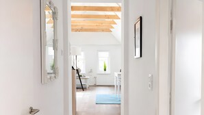 A staircase leading to a room with a wooden ceiling, white walls, and a blue mat on the floor.