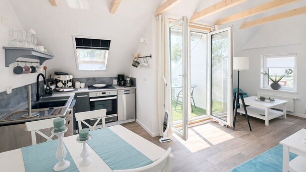 A modern kitchen with a dining area, large windows, and a view of the outdoors.