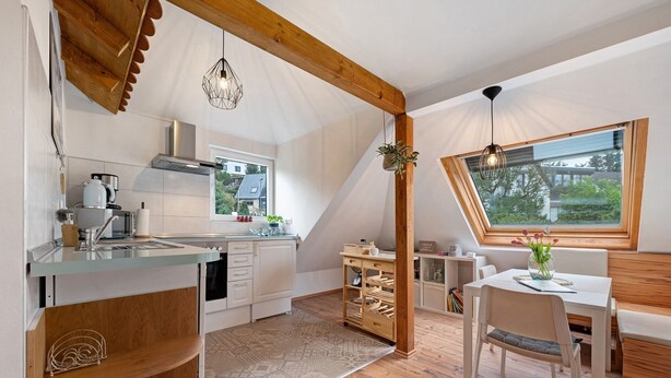 Une cuisine moderne avec un coin repas, des poutres en bois et une grande fenêtre.