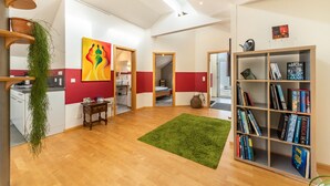 Um interior moderno com piso de madeira, um tapete verde, uma estante de livros e um quadro.