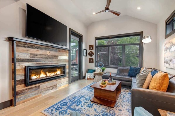 Un salon moderne avec une cheminée, un téléviseur à écran plat, un canapé et une table basse.