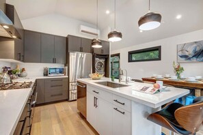 A modern kitchen with a central island, stainless steel appliances, and pendant lighting.