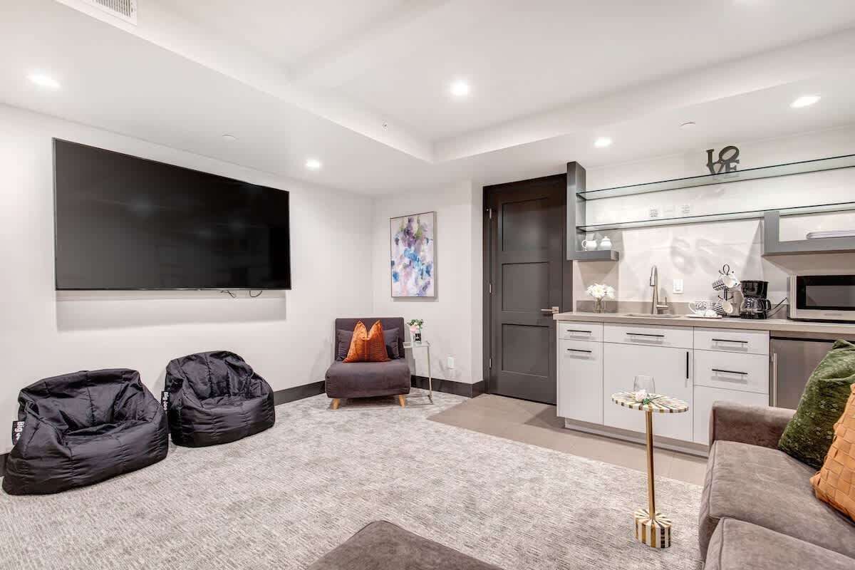 Een moderne woonkamer met een flatscreen televisie, een bank, een salontafel en een kitchenette.