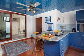 A modern kitchen with blue cabinets, a wooden island, and a ceiling fan. - Seafront Adriatic Pearl Suite, Kraljevica, Croatia (Kraljevica)