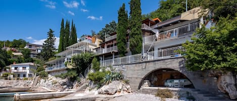 A coastal property with a stone bridge, clear water, and lush greenery.