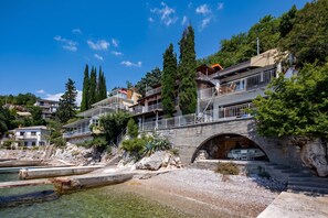 A coastal property with a stone bridge, clear water, and lush greenery. - Seafront Adriatic Pearl Suite, Kraljevica, Croatia (Kraljevica)
