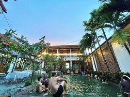 Un patio con piscina, palmeras y un edificio con balcón.