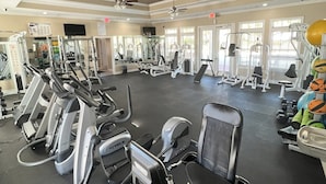 Une salle de sport équipée de divers appareils d’exercice, notamment des tapis de course et des appareils de musculation, disposés en rangées.