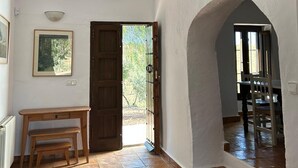 A spacious room with a wooden bench, a door leading outside, and a view of a dining area. - Burruelo Ranch in Algodonales (Algodonales)