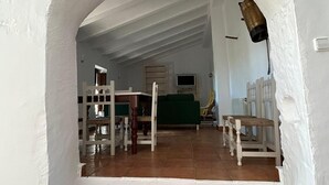 A room with a white arched doorway leading to a living area with a green sofa, wooden chairs, and a tiled floor. - Burruelo Ranch in Algodonales (Algodonales)
