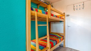 A bunk bed with colorful bedding, a white door, and a wall-mounted hook. - Studio Apartment 'Les Ptits Loups, Le Grau D'agde' with Sea View and Air Conditioning (Agde)