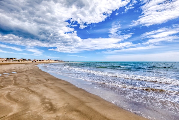 A beach with a sandy shore, ocean waves, and a partly cloudy sky.