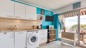A compact kitchen with a washing machine, a microwave, and a flat-screen TV. - Studio Apartment 'Les Ptits Loups, Le Grau D'agde' with Sea View and Air Conditioning (Agde)