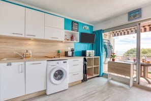 Une cuisine compacte équipée d’un lave-linge, d’un four à micro-ondes et d’un téléviseur à écran plat.
