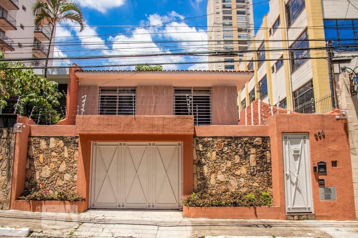 Una casa de dos pisos con fachada de piedra, un gran portón de garaje y un pequeño balcón.