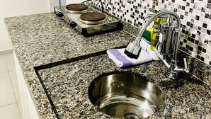 A kitchen with granite countertops, a stainless steel sink, a gas stove, and a tiled backsplash. -  Vila Nina (São Paulo)