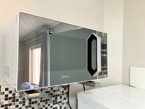 Un baño con lavamanos blanco, espejo y salpicadero de azulejos.