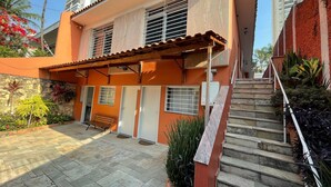 A two-story building with a tiled patio, a wooden bench, and a staircase leading to the upper floor. -  Vila Nina (São Paulo)