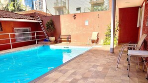 A swimming pool with tiled flooring and metal chairs. -  Vila Nina (São Paulo)