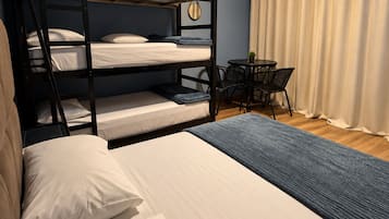 Habitación con literas, un televisor de pantalla plana, una mesita pequeña y una cortina.