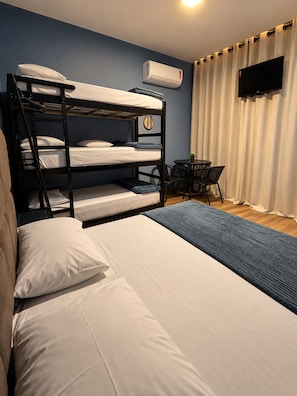 A bunk bed room with a flat-screen TV, a small table, and a curtain.