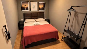 A hotel room with a bed, a wall-mounted air conditioner, and framed pictures.