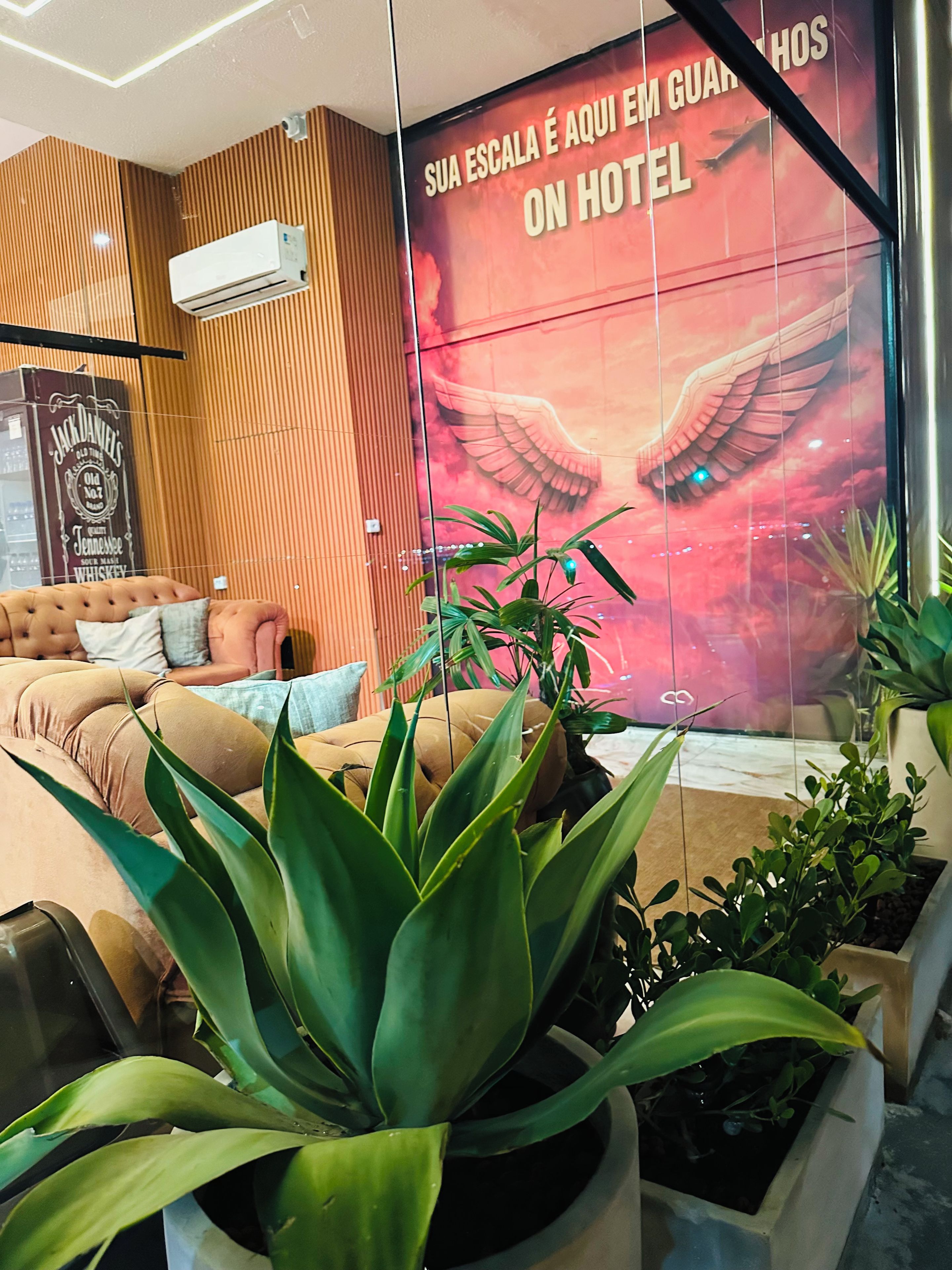 A hotel lobby with a large wall mural, a seating area with sofas, and potted plants.