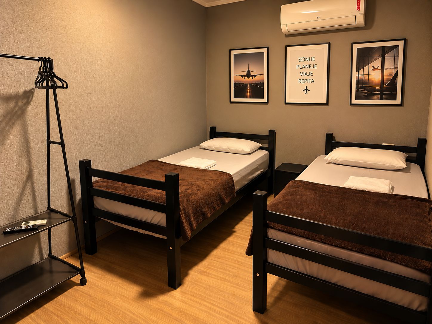 Ein Zimmer mit zwei Einzelbetten, einem Regal mit Fernbedienung und Wandklimaanlage.