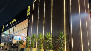 Een hotel met een moderne gevel, grote potplanten en een bord waarop staat dat het een hotel is.