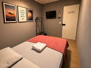 A hotel room with a bed, a TV, a door, and three framed pictures on the wall. - On Park Hotel Translado e Café da manhã (Guarulhos)
