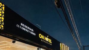 Un hôtel doté d’une façade en verre, d’un espace de réception avec un canapé et de plantes en pot à l’extérieur.