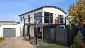 Ein modernes, zweistöckiges Haus mit Balkon, Garage und einem umzäunten Garten.