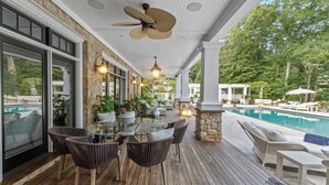 Un espace extérieur abrité comprenant une piscine, des meubles en osier et une table en verre.