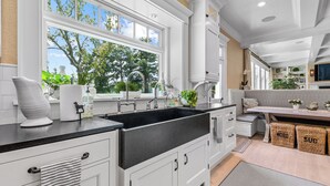 Une cuisine moderne dotée d’une grande fenêtre, de meubles blancs et d’un plan de travail noir.