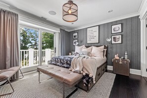 A bedroom with a large bed, a bench, a nightstand, and a view of the outdoors. - Gorgeous, Peaceful Sanctuary on lake minutes from Boston & all local colleges. (Wayland)