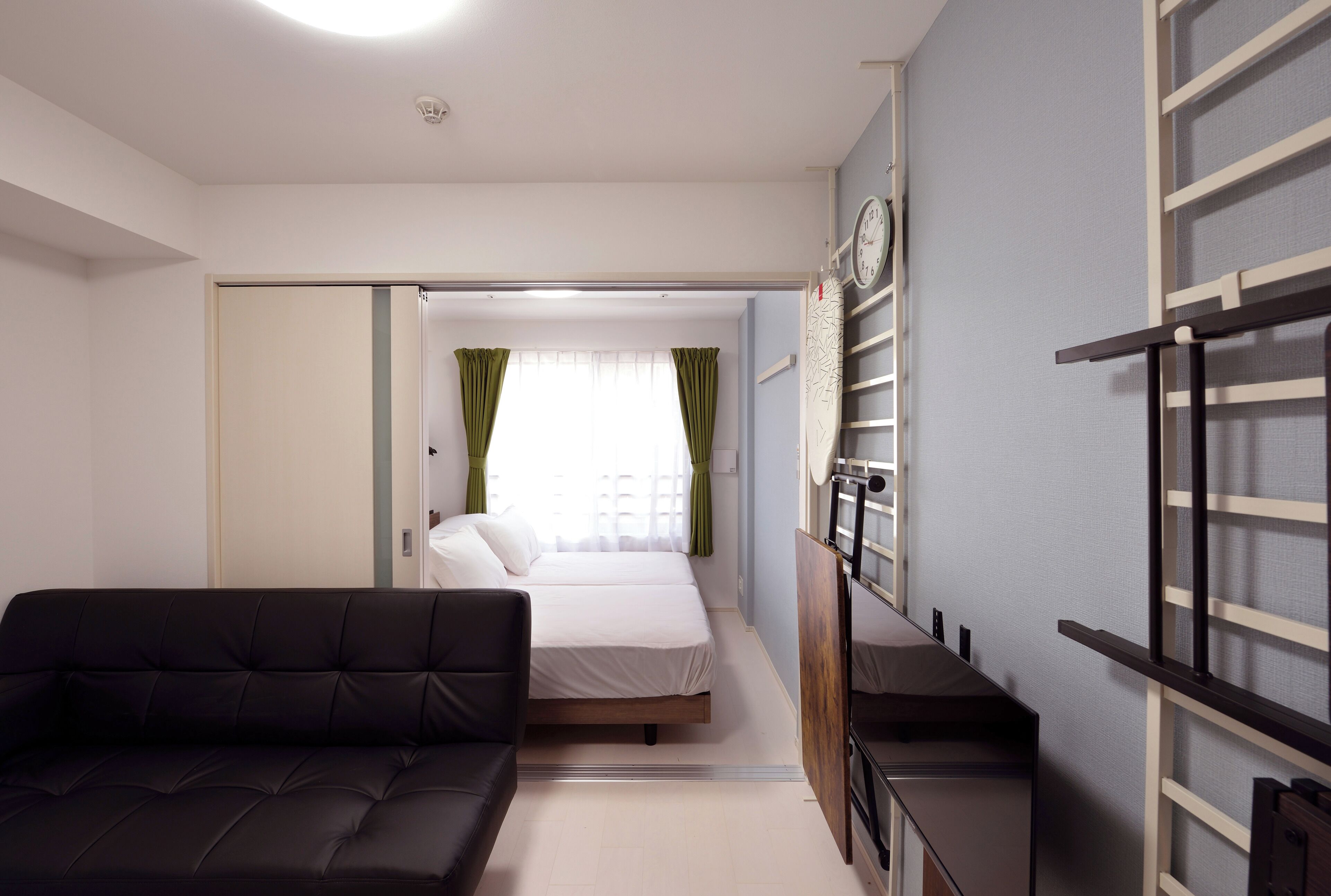 A compact hotel room with a bed, a sofa, a desk, and a wardrobe.