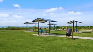 Un parc équipé de tables de pique-nique, de bancs et d’une aire de jeux.