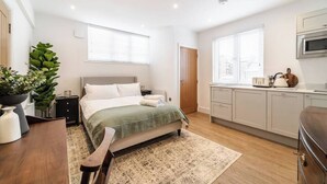 A modern bedroom with a bed, bedside tables, a desk, and a potted plant. - Spacious Stylish Studio, Hoylake (Hoylake)