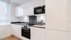 Uma cozinha moderna com armários brancos, um micro-ondas Bosch e forno embutido.