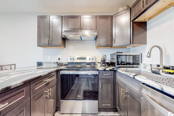 Enjoy cooking in this well-equipped kitchen with oven and microwave, complemented by dark cabinetry.
