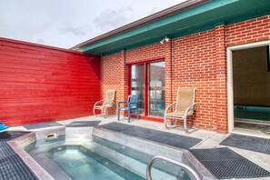 Relax in a hot tub surrounded by a metal barrier, accessible via steps, with two chairs nearby.