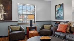 Ein modernes Wohnzimmer mit einer Couch, zwei Sesseln, einem Couchtisch und einer Lampe.