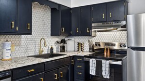 A modern kitchen with black cabinets, a stainless steel refrigerator, a built-in oven, and a microwave.