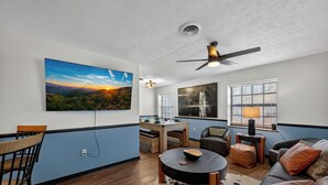 Ein modernes Wohnzimmer mit Essbereich, Deckenventilator und Kunstwerken an den Wänden.