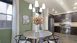 A modern kitchen with dark cabinets, stainless steel appliances, and a round dining table with chairs.